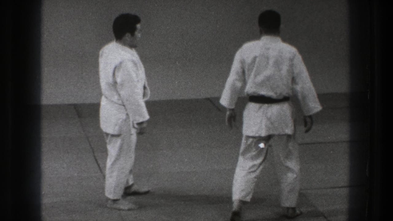 The 1971 Tokyo judo scene shows two adult men standing apart on the tatami, with one turned away as practice continues.