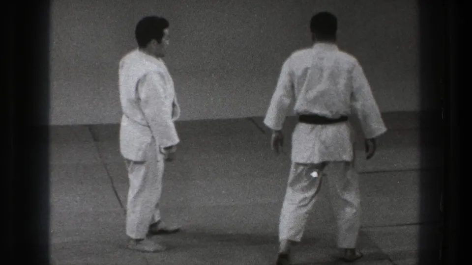 The 1971 Tokyo judo scene shows two adult men standing apart on the tatami, with one turned away as practice continues.