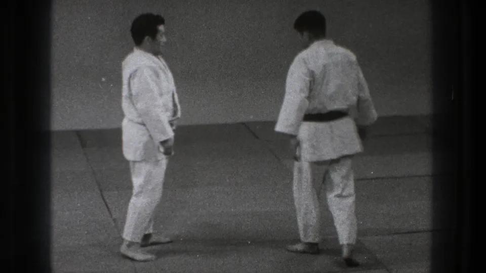In Tokyo, Japan, 1971, two adult judo practitioners in white gi stand on a mat before beginning a demonstration.