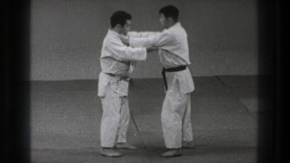 The 1971 Tokyo home-movie frame shows the pair holding gi grips and adjusting balance during the throwing-technique setup.