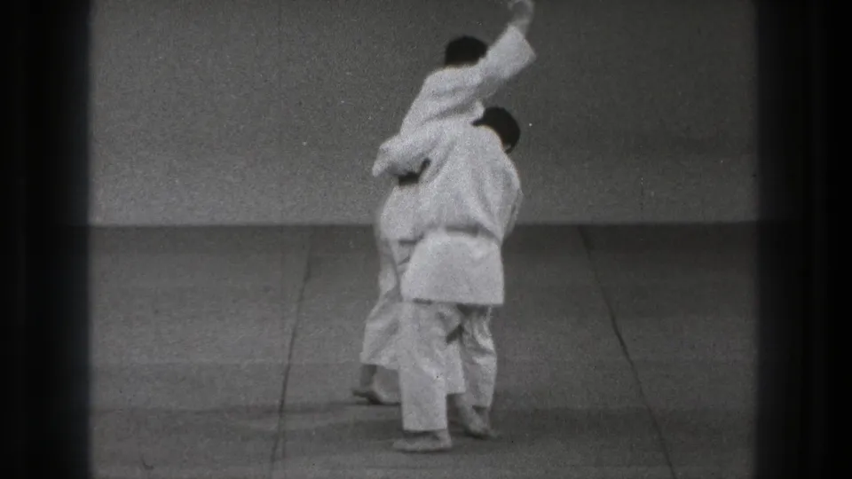 One adult man in a white uniform appears to execute a throwing move on his partner in 1971 Tokyo footage.