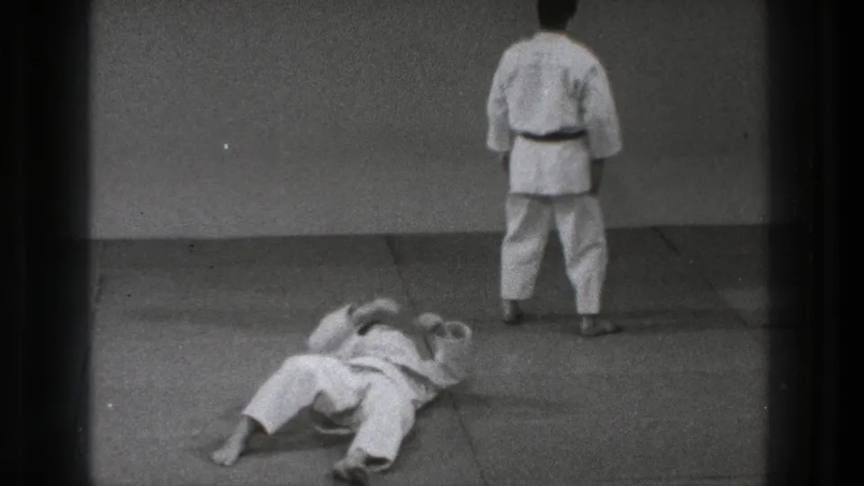 After the throw, one participant lies on his back while another stands facing the wall in the 1971 Tokyo practice footage.