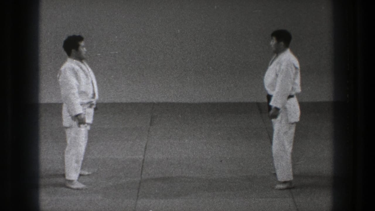 The 1971 Tokyo home-movie frame shows two men in gi standing opposite each other on a simple dojo mat before practice resumes.