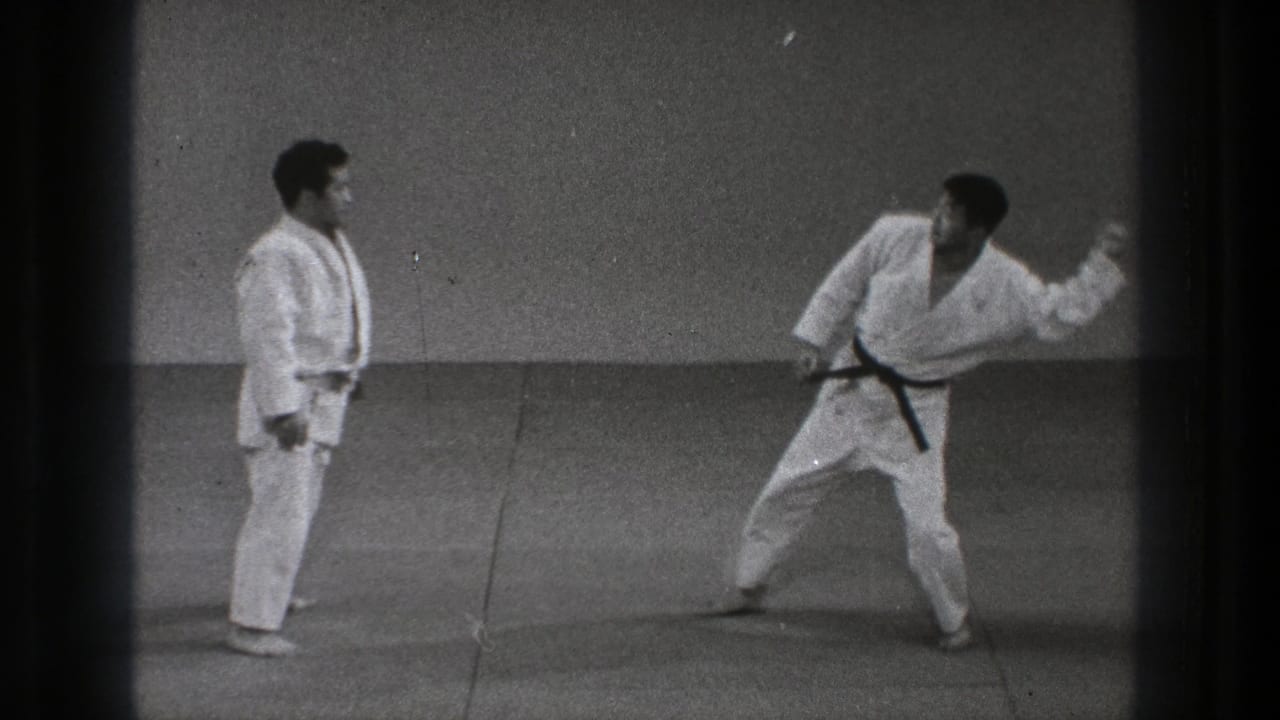 Two men in white gi face each other on a mat, one wearing a black belt.