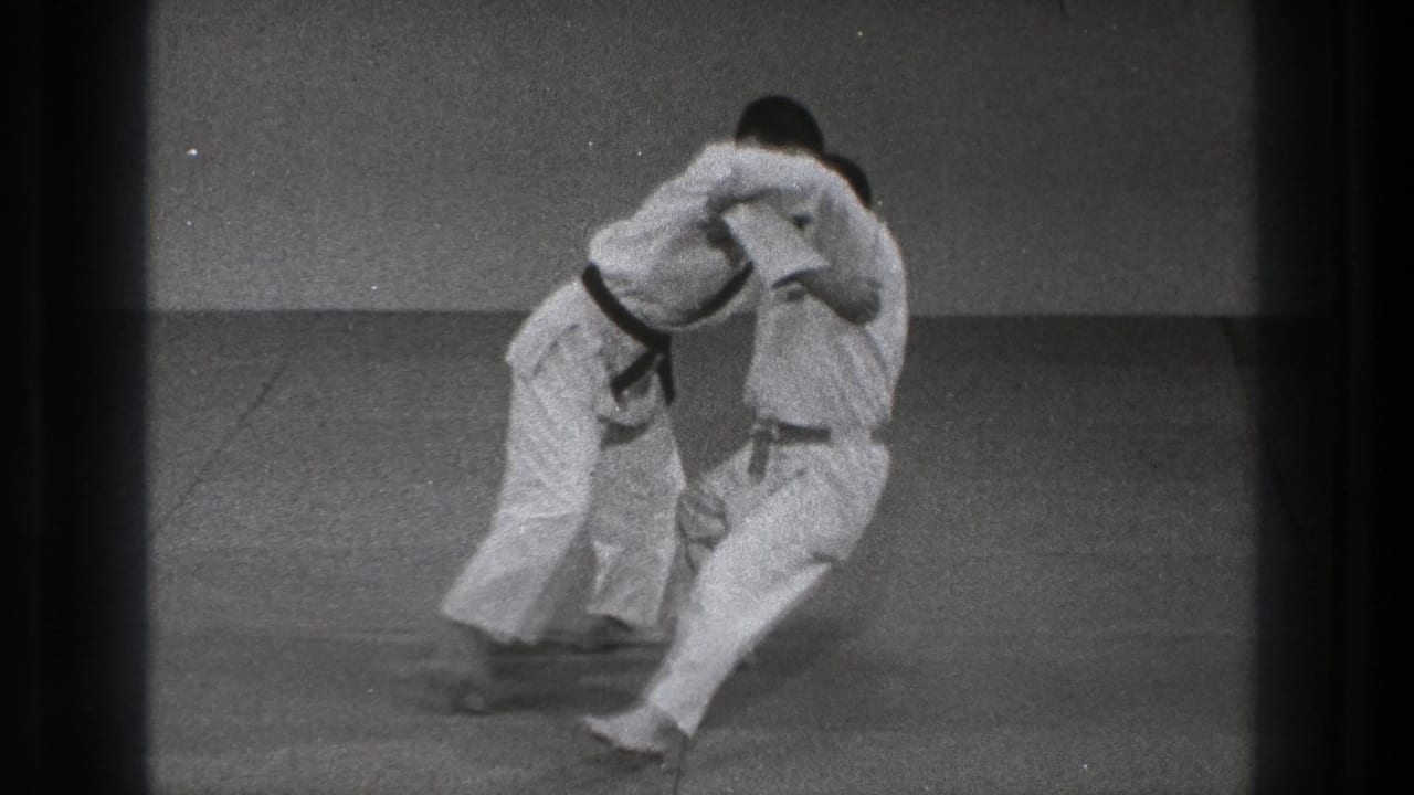 Near the end of the 1971 Tokyo clip, one karate practitioner draws the other into an off-balance takedown motion.