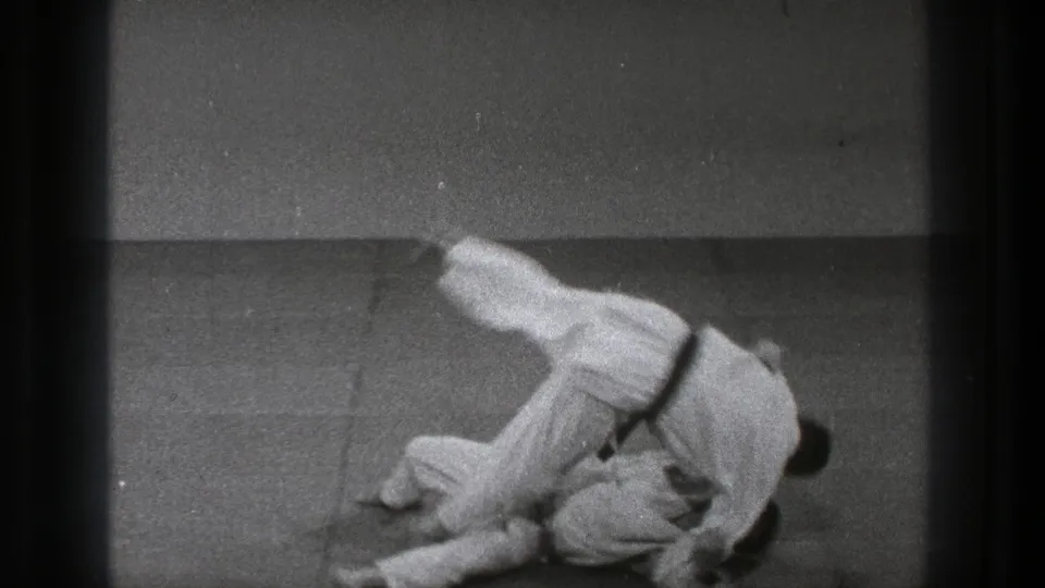 Tokyo 1971 8mm frame showing two martial artists in white gi on a padded mat during a throw.