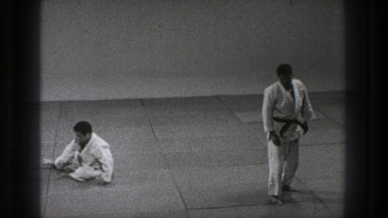 Tokyo 1971 8mm frame showing one martial artist seated on the mat and another standing after practice movement.