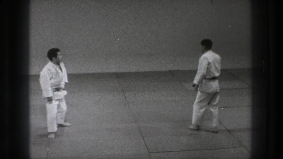 1971 Tokyo 8mm frame showing two adult martial artists in white gi facing each other across a mat area.
