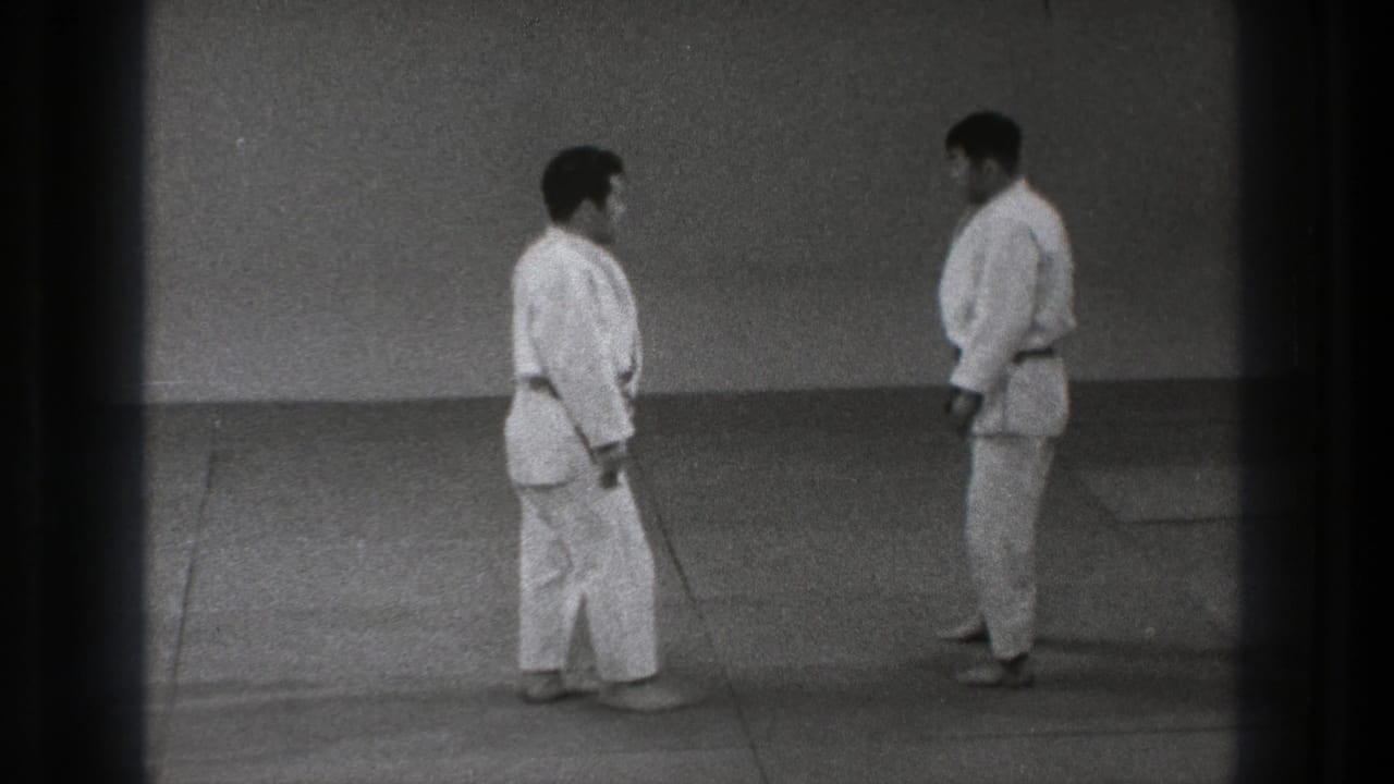 Two adult martial artists in gi stand face to face on a dojo mat during a formal pre-match moment in Tokyo, 1971.