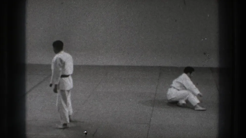 The sequence ends with one adult martial artist standing at left while the other sits up on the mat in the 1971 Tokyo footage.