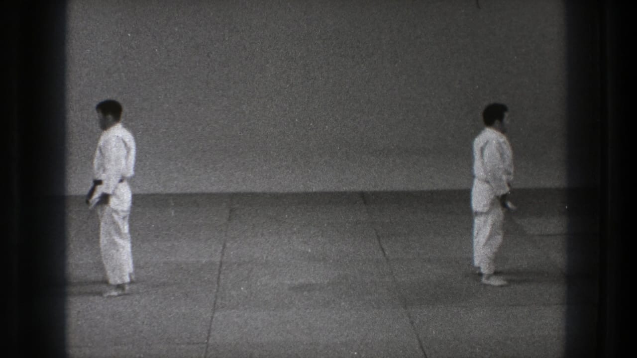 Two karate practitioners in white gi stand apart on a training floor.