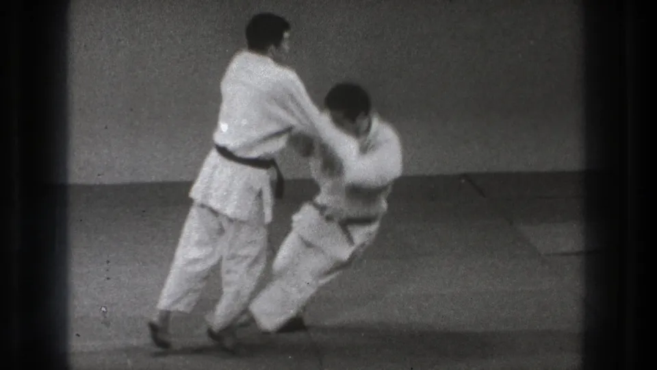 Near the end of the sequence, one practitioner is low to the mat while the standing partner maintains control of the throw.