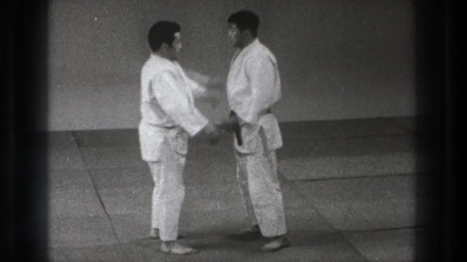 A karate practitioner reaches toward his partner during a controlled 1971 Tokyo self-defense demonstration.