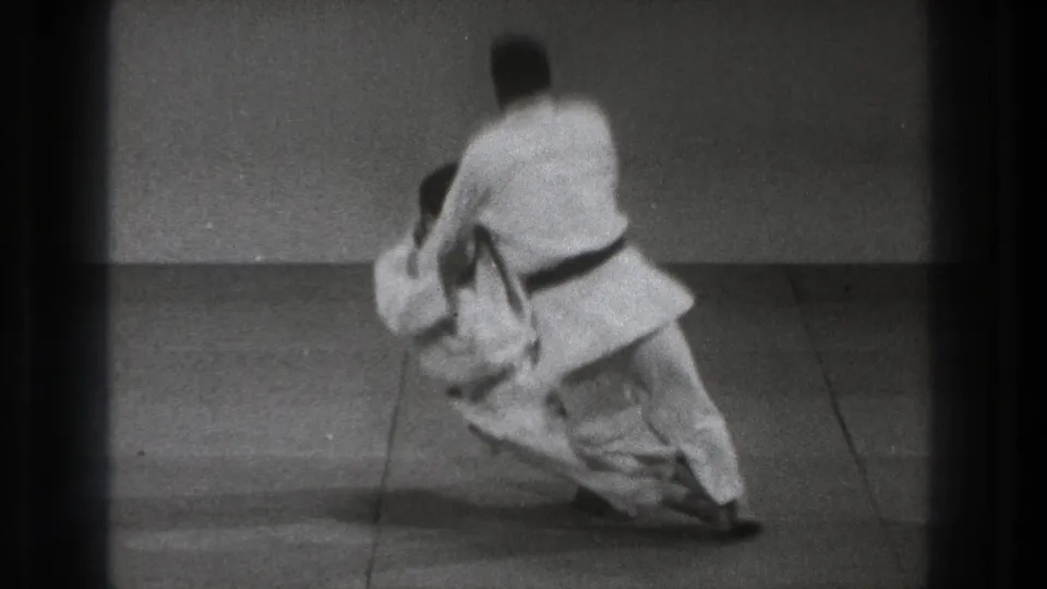 The 1971 Tokyo footage shows a black-belt practitioner executing a judo throw as the partner falls toward the mat.