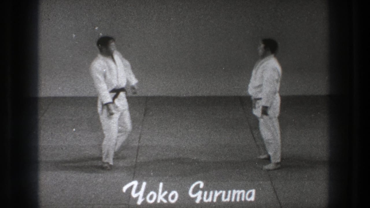 Two men in white gi face each other on a mat with handwritten Yoko Guruma text.