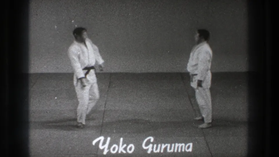 1971 Tokyo 8mm frame showing two karate practitioners in white gi facing each other beside a handwritten Yoko Guruma title.