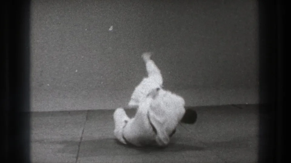 The sequence ends with one karate practitioner down on the mat and the other nearby after a controlled defensive throw.