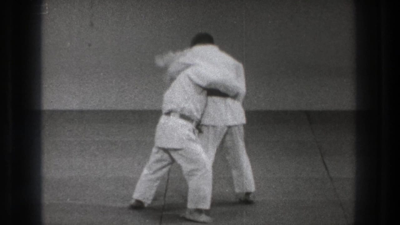 A judo practitioner in a white gi steps inside and lowers his stance while maintaining a body grip during practice in Tokyo, 1971.
