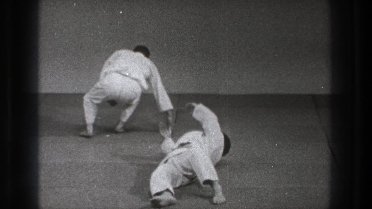 A 1971 Tokyo martial arts practice frame shows one man rising or stepping away as his partner lies on the mat after a throw.