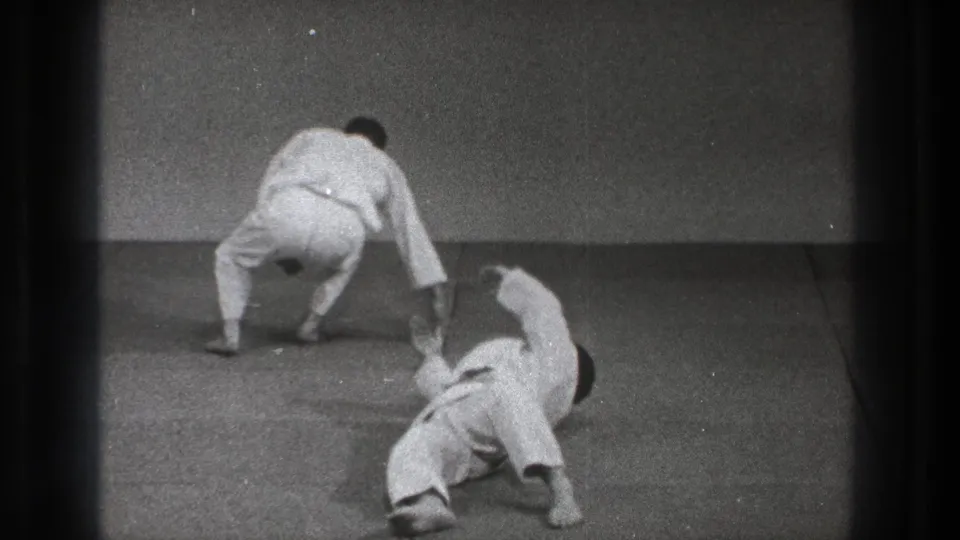 A 1971 Tokyo martial arts practice frame shows one man rising or stepping away as his partner lies on the mat after a throw.