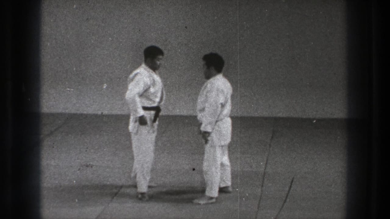 Two men in white gi face each other on a mat, one wearing a black belt.