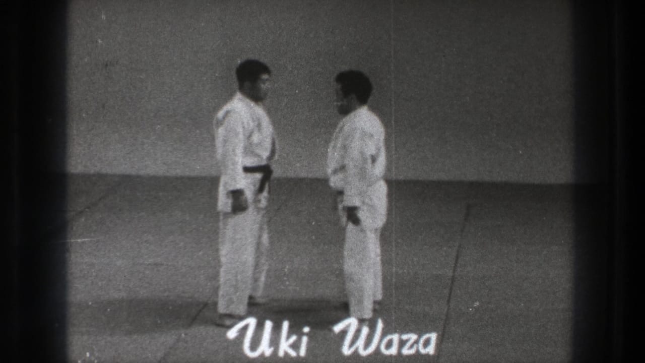 The two practitioners face each other on the mat as a handwritten Uki Waza title appears over the 8mm frame.