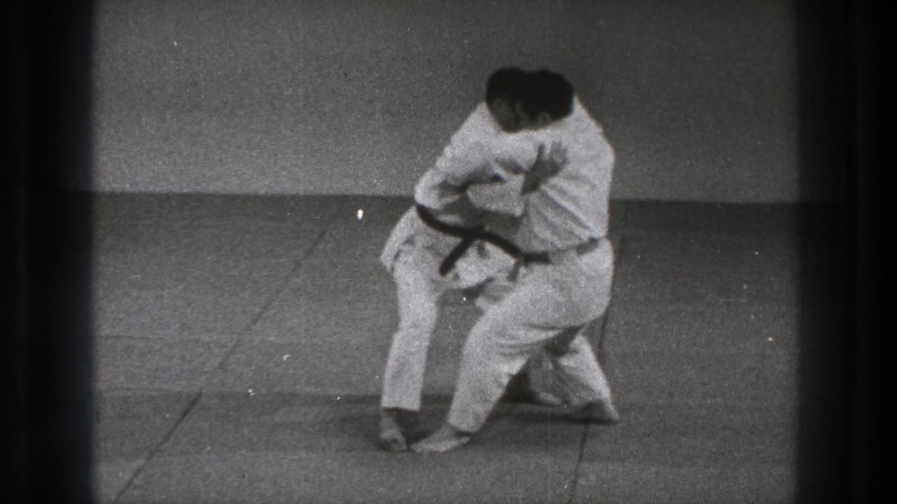 A 1971 Tokyo martial arts drill shows one man lowering his stance while maintaining a hold on his partner.