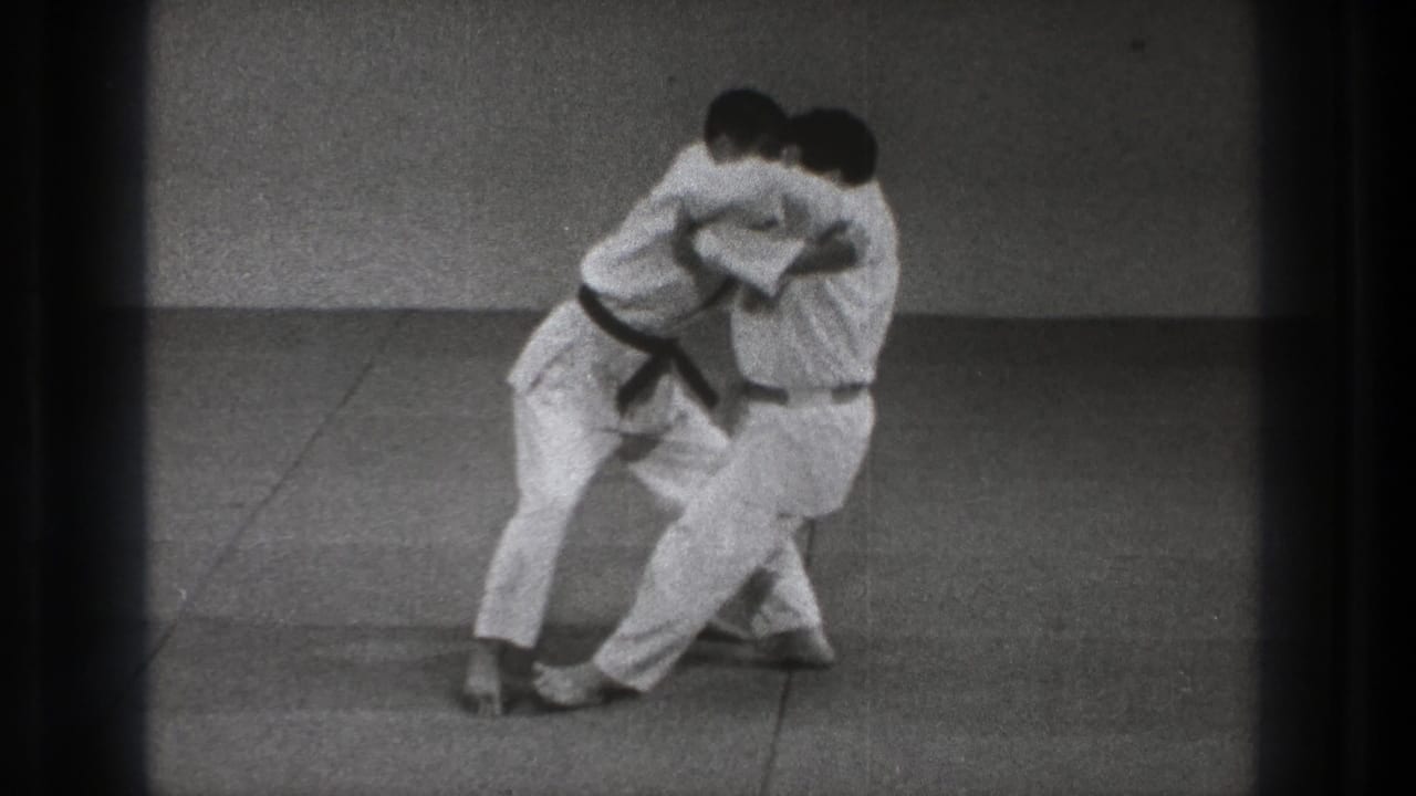Near the end of the 1971 Tokyo clip, two gi-clad men shift through a controlled grappling motion on mats.