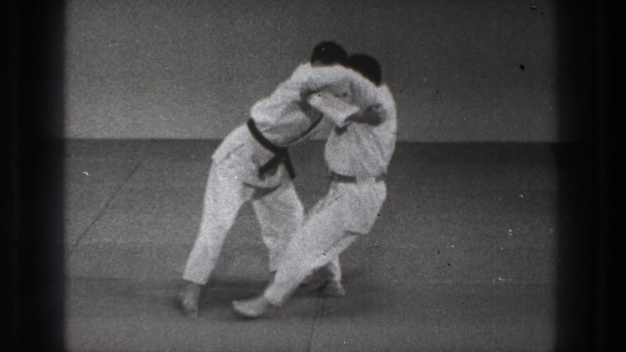 In the Tokyo 1971 8mm frame, two men in white gi lean together as a grappling throw shifts one participant off balance.