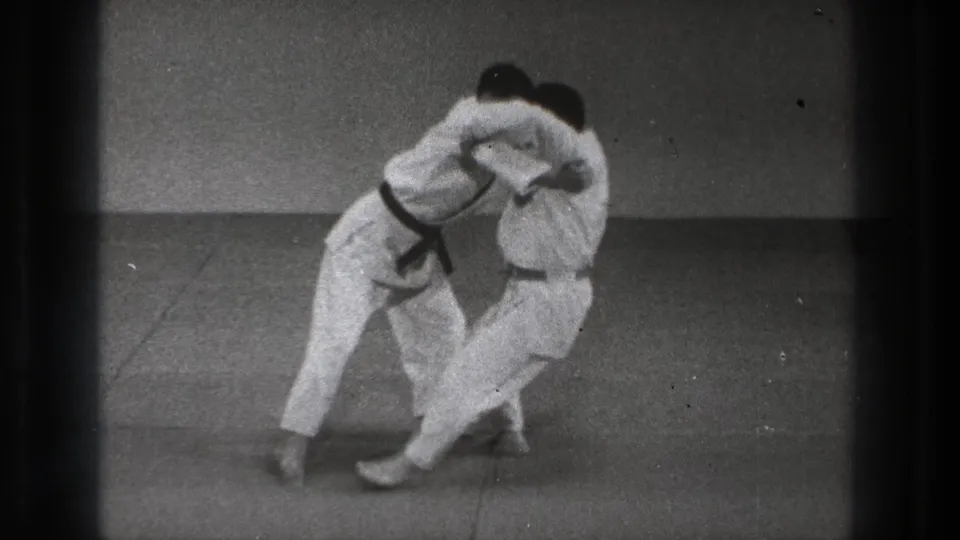 In the Tokyo 1971 8mm frame, two men in white gi lean together as a grappling throw shifts one participant off balance.