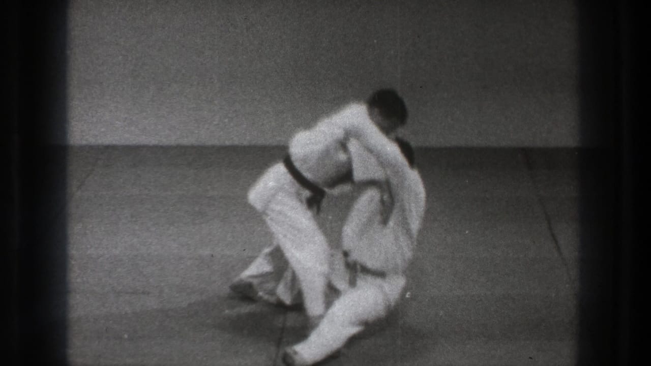 The throw finishes with one man low on the mat and the other leaning above him in black-and-white 8mm Tokyo 1971 footage.