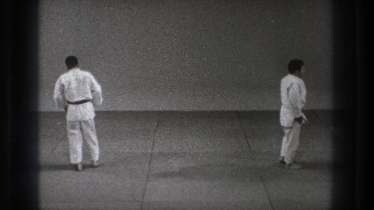 A 1971 Tokyo frame shows two men in white martial arts uniforms standing apart on a grey practice mat, framed by dark 8mm borders.