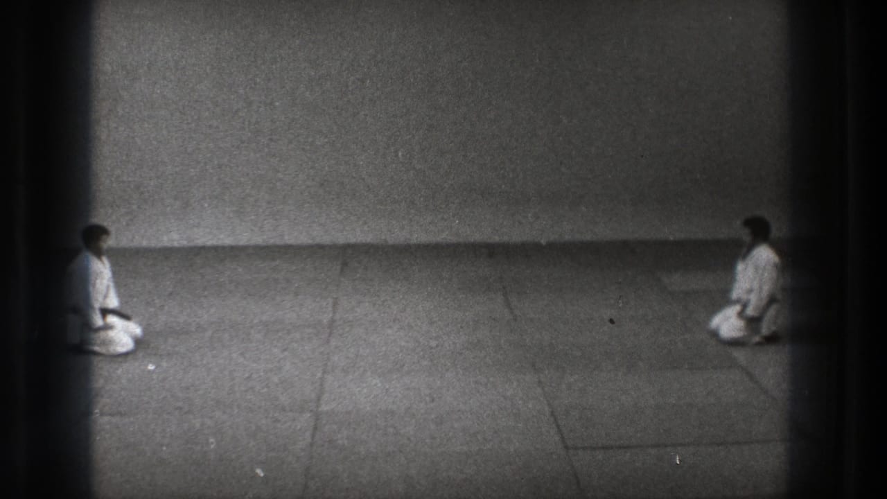Two karate practitioners remain kneeling at opposite ends of the mat in grainy 1971 Tokyo 8mm footage.