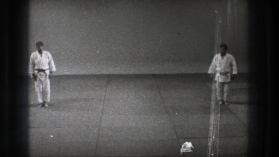 Black-and-white 8mm view from Tokyo 1971 showing two karate practitioners standing apart after bowing.