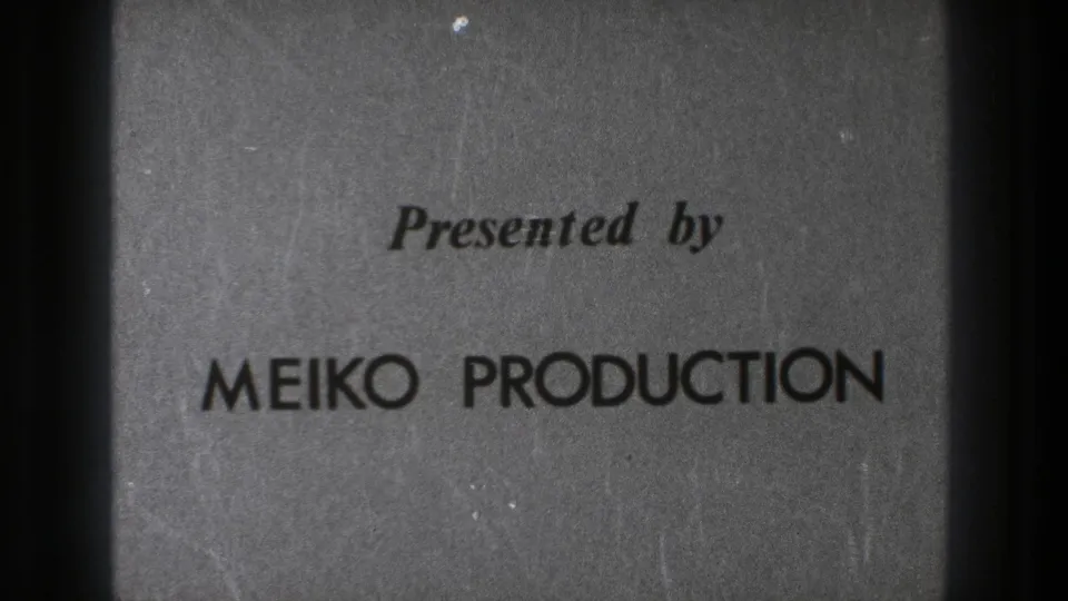 1971 Tokyo 8mm frame of the MEIKO PRODUCTION title card, with grain, soft focus, and dark edge shadowing.