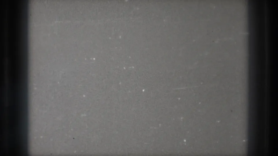1971 Tokyo 8mm frame of a grey, untuned television-like screen with dark edge bars, grain and small white specks.