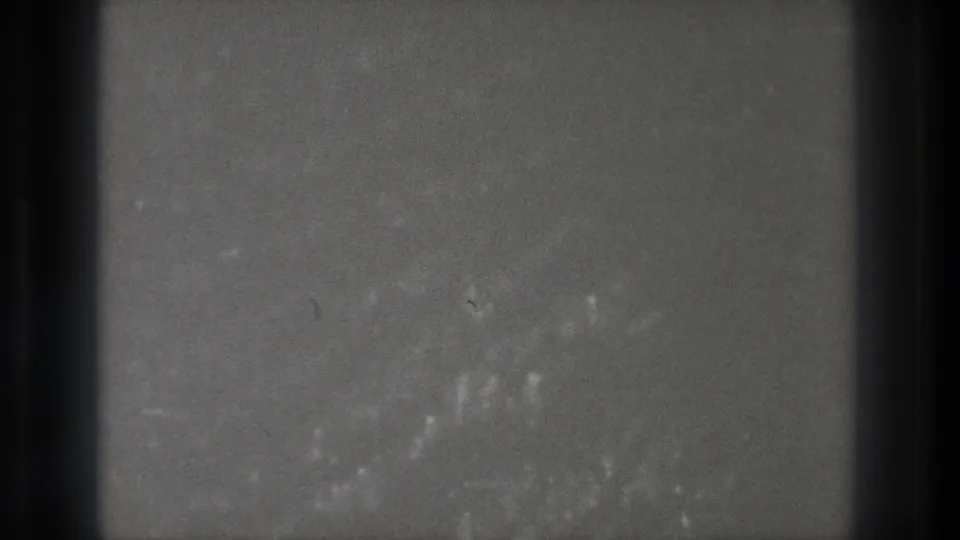 1971 Tokyo 8mm frame showing grey television static, dark vertical screen bands and brighter film marks near the lower right.