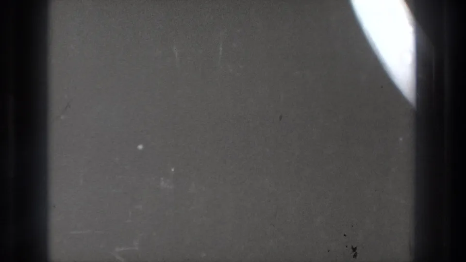 Tokyo 1971 8mm home-movie frame showing a partial overexposed diagonal streak against a dark, grainy film field.