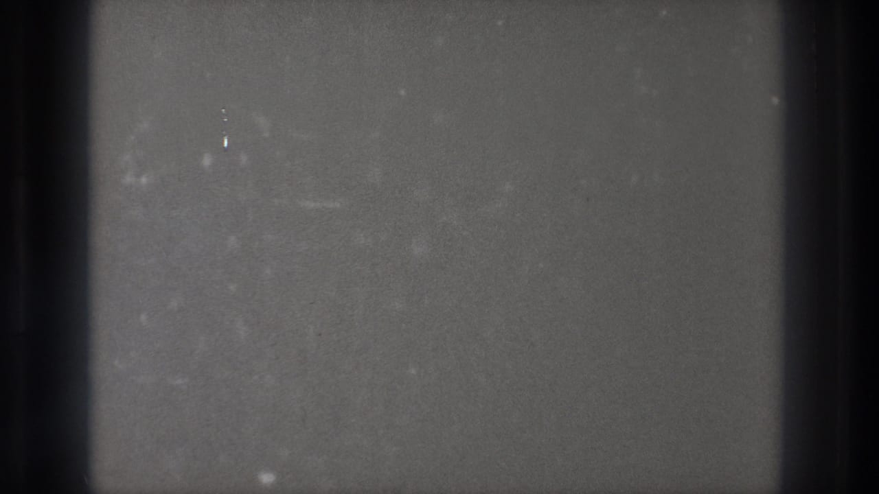 Gray textured film frame with central dark edge band, dust, scratches, and uneven exposure.