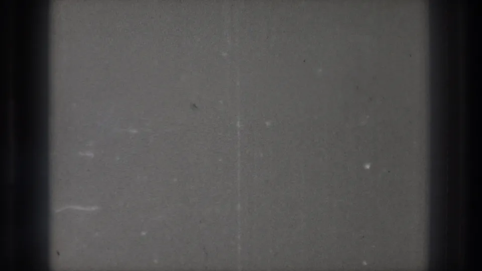 Blank gray 8mm frame from the 1971 Tokyo reel, showing dark film edge, scattered dust, grain, and subtle scratches.