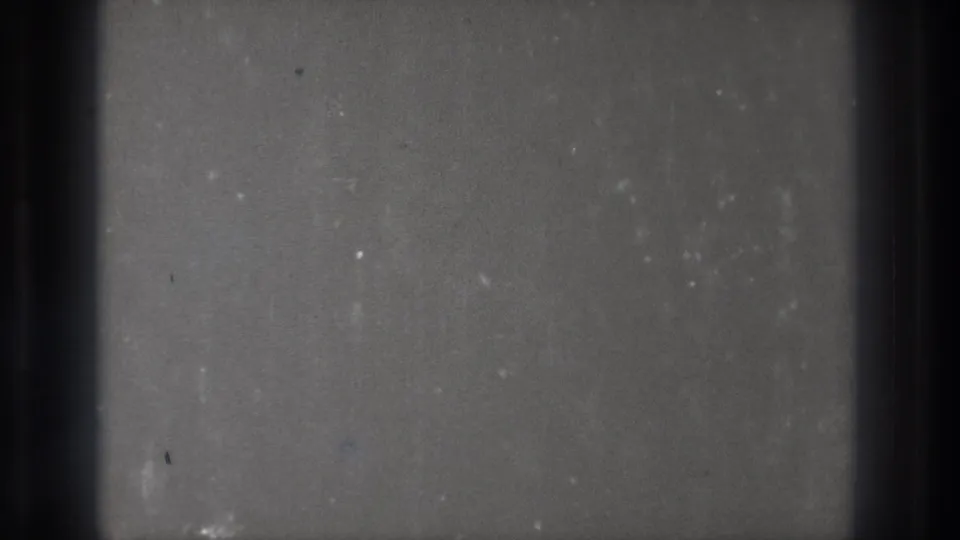 Blank 8mm frame from the Tokyo Japan 1971 source, with gray grain, dust specks, faint stains, and dark frame edges.