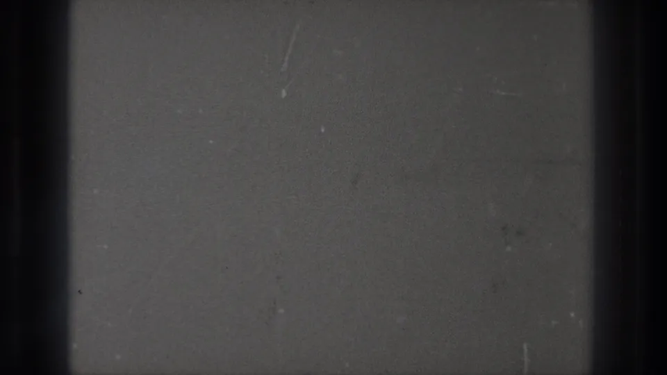 1971 Tokyo 8mm footage showing a close view of film passing through projection, with gray frame areas, dark bars, dust, and scratches.