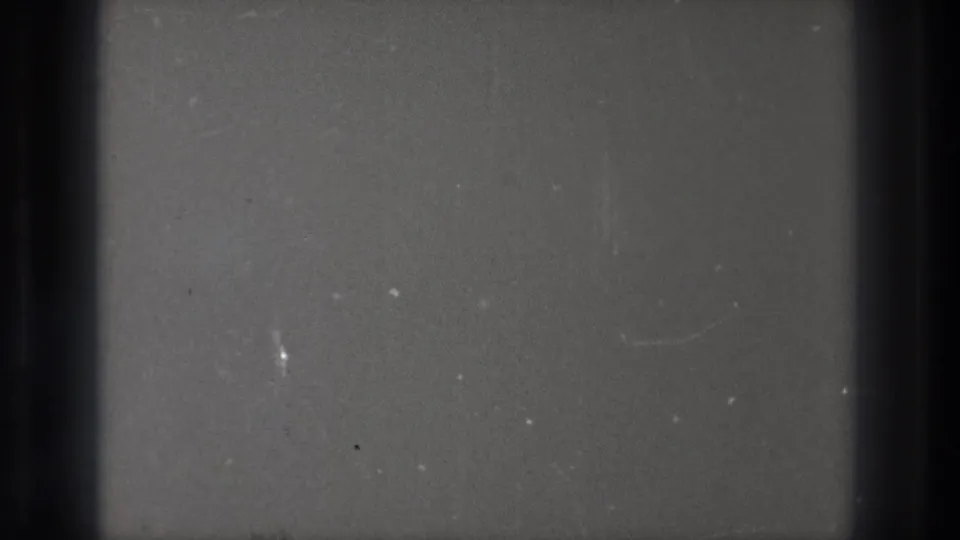 Close view of 8mm film texture from 1971 Tokyo footage, with dark vertical bands, dust, scratches, and a faint horizontal boundary.
