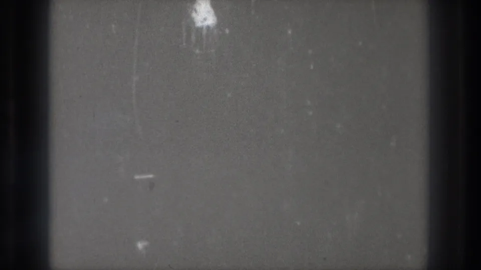 Blank 8mm film from a 1971 Tokyo reel, showing gray emulsion, dark frame edges, dust, and light surface scratches.