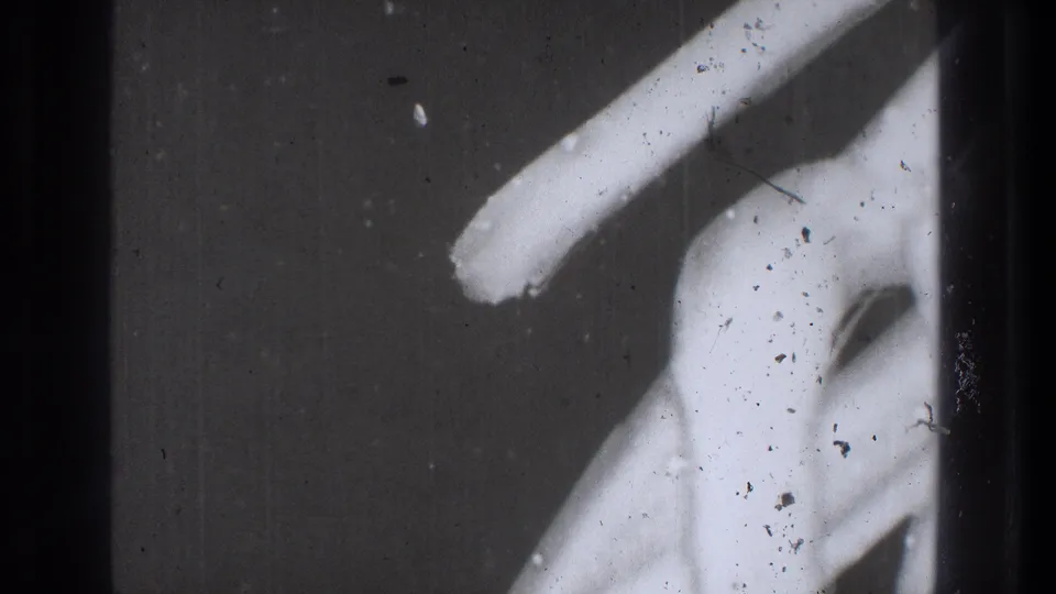 1971 Tokyo 8mm frame with repeated abstract white light forms, dust, scratches, and dark edge bands.