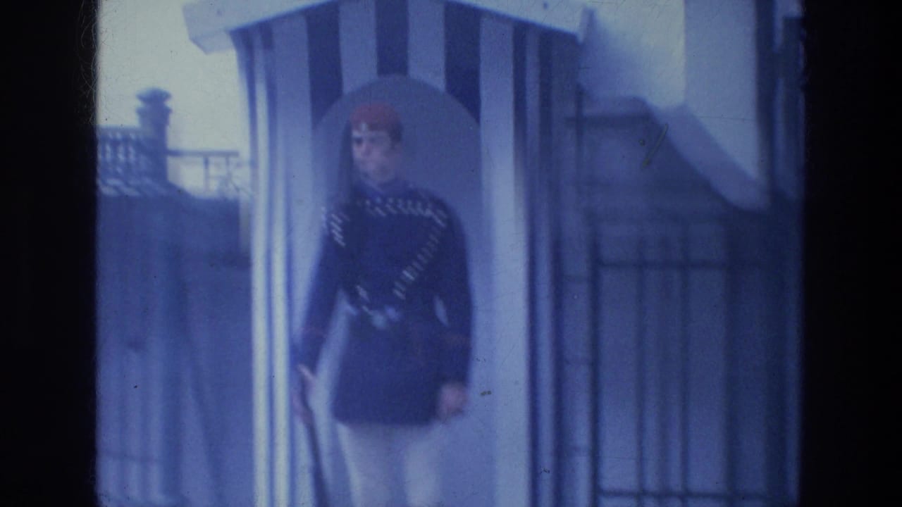 Uniformed guard stands beside a striped sentry box near a building entrance.