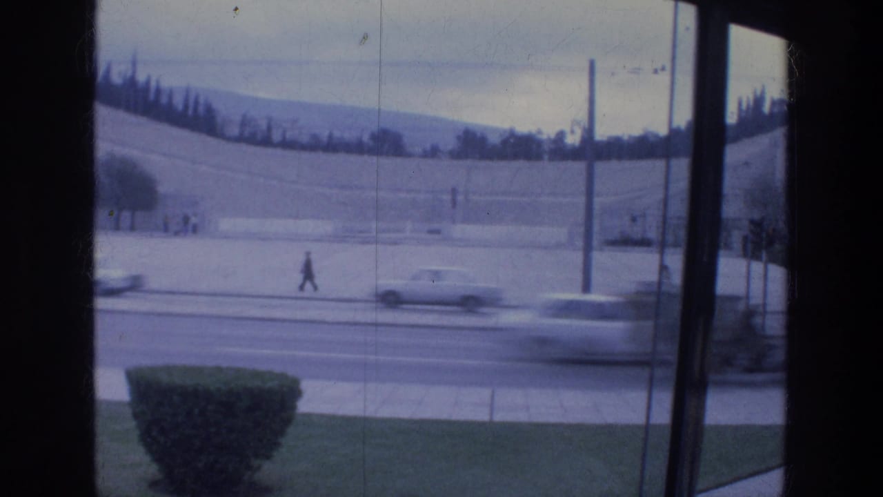 Street seen through a window frame with cars passing and a pedestrian near the road.