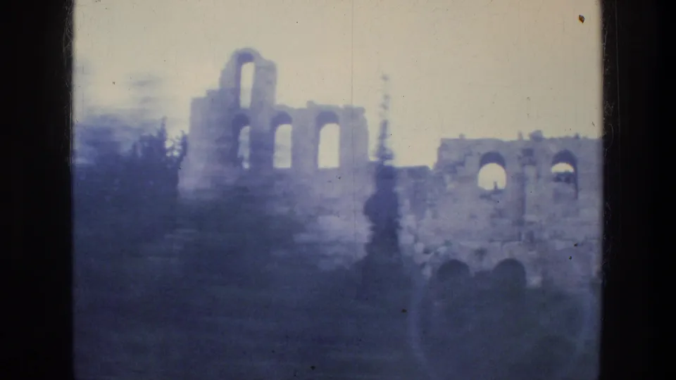 1976 Athens travel-home-movie frame showing weathered stone arches and surrounding greenery in soft focus.