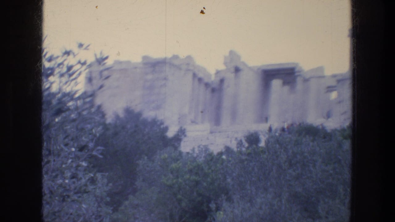 Distant ancient stone ruins and columns above trees under a pale sky.