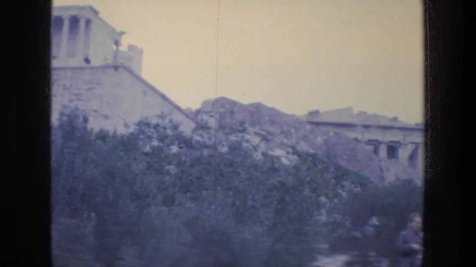 Final 1976 Athens frame with Acropolis stonework and partial ruins visible over trees in faded 8mm color.